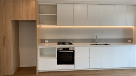 Camberwell apartment showcasing the kitchen's oven, cook top, sink, white cupboard and ref cavity