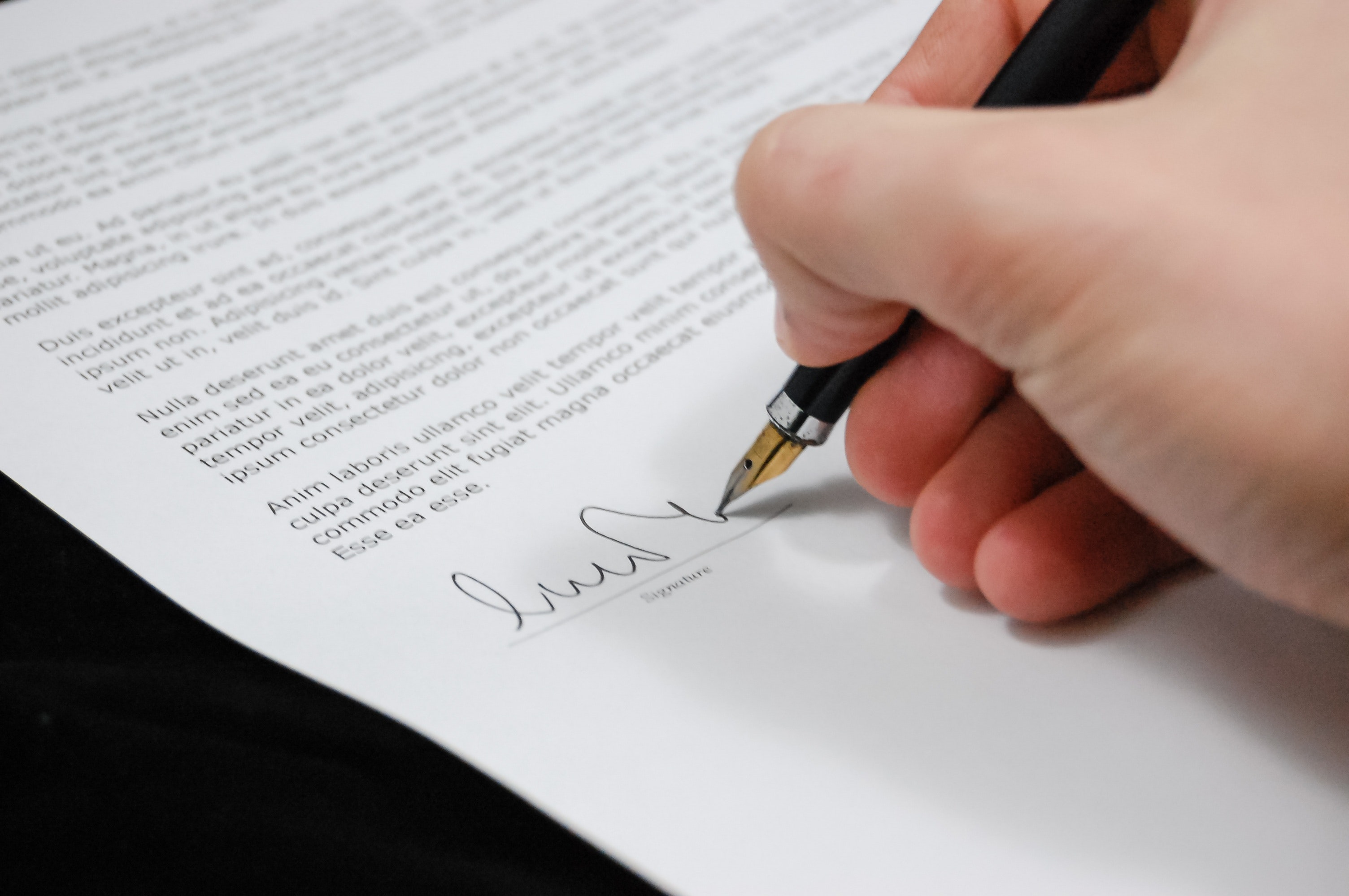 A hand signing a paper